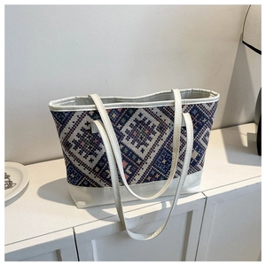Detail showing geometric woven ethnic patterns and white leather trim on tote bag