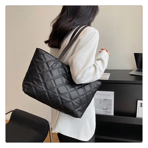 Detail of black quilted tote bag showing matte texture and large capacity for commuting