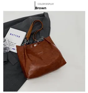 Détail d'un sac cabas marron vintage en similicuir avec chaîne en métal et logo