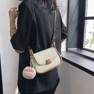 Petit sac à bandoulière beige minimaliste avec passepoil marron et breloque pêche