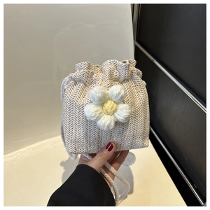 Close-up of beige crochet bucket bag featuring a handcrafted white flower decoration