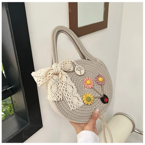 Détail du sac à main rond tissé orné d'un nœud en dentelle et de fleurs en tissu