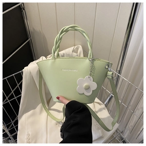 Detail of light green PU leather handbag with woven handle and flower pendant in a cart