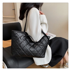 Detail of black quilted tote bag showing rhombus texture and slim shoulder straps