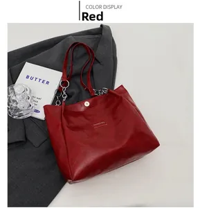 Détail du sac cabas rouge avec chaîne en métal et fermeture magnétique sur fond blanc