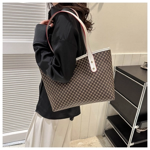 Side view of large brown pattern tote bag with white leather straps on female model