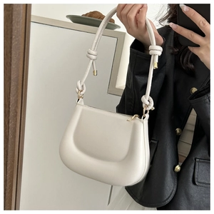 Detail of off-white faux leather hobo bag showing knotted strap and gold hardware