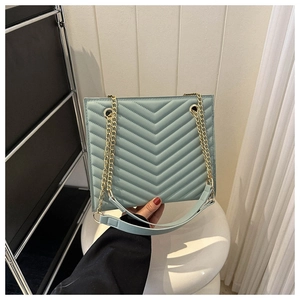 Close-up of V-shaped quilted leather texture and gold metal chain strap on light blue tote