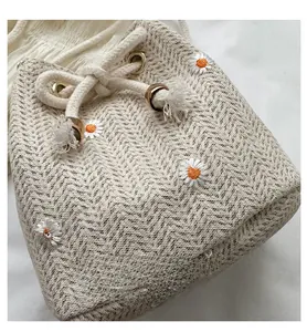Detail of woven bucket bag featuring small daisy embroidery and hemp drawstring closure