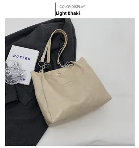 Vue détaillée du sac cabas kaki clair avec bandoulière chaîne et logo de mode élégant