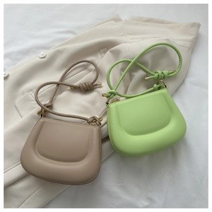 Detail of minimalist handbags with knot shoulder straps and gold metal tips on a blazer