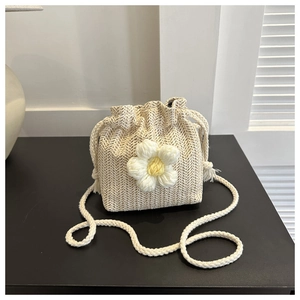 Detail of cream woven bucket bag with handmade knit flower and drawstring closure