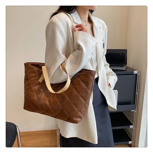 Detail of a brown quilted tote bag showing high-quality diamond texture and beige handle