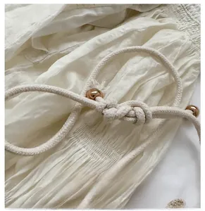 Detail of hand-woven cotton drawstring with gold metal beads on a cream bucket bag