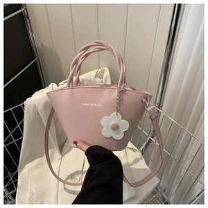 Pink fan-shaped leather handbag with woven handles and floral charm detail