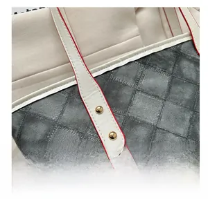 Détail du sac cabas en denim à carreaux avec poignée en cuir blanc et bords rouges vifs
