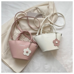 Flat lay of pink and ivory mini bucket bags with cute flower charms on a stylish blazer