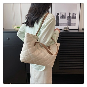 Quilted tote bag in cream white with brown leather straps shown in a modern home setting