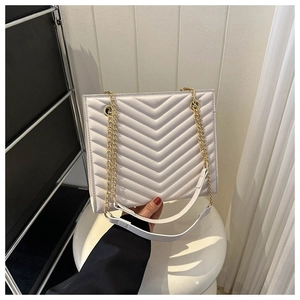 Detail of white chevron quilted bag showing gold chain strap and elegant leather finish