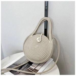 Gros plan du sac en paille rond avec texture tressée, poignées et étiquette en bois