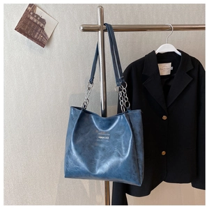 Détail du sac cabas bleu avec bandoulière en chaîne métallique et logo mode embossé