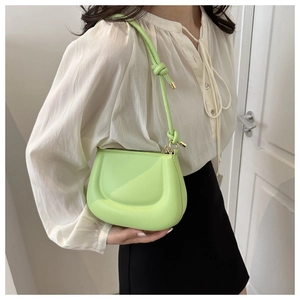 Close-up of neon green shoulder bag featuring a knotted strap and golden zipper detail