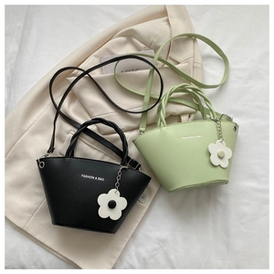 Detail of minimalist bucket bags in black and mint green with flower charms and long straps