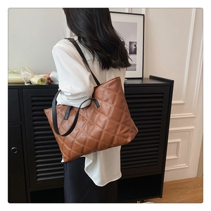 Close-up detail of a brown quilted tote bag with diamond stitching and black straps