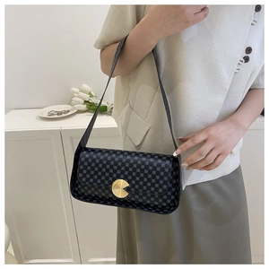 Détail du sac à bandoulière noir avec pois bleus et boucle métallique dorée circulaire