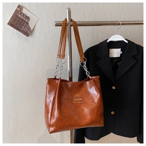 Détail d'un sac cabas marron en similicuir avec bandoulière chaîne et étiquette mode