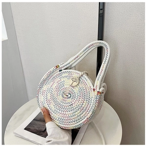 Détail d'un sac rond en paille avec coutures zigzag colorées et pendentif bois
