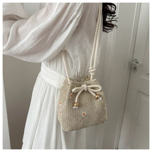Detail of woven bucket bag featuring floral embroidery and cotton rope drawstring closure