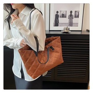 Detailed close-up of brown quilted nylon tote bag with black straps and soft texture