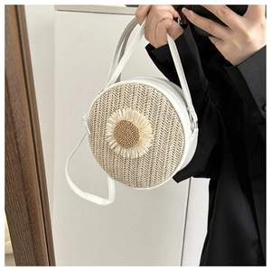 Détail d'un sac rond en paille avec bordure en cuir et motif tournesol