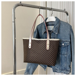 Detail of medium tote bag featuring brown geometric pattern and white leather handles