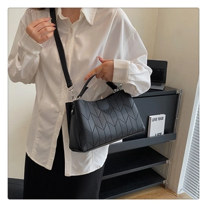 Detail view of black tote bag with geometric V-shaped stitching and adjustable strap