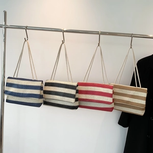 Large striped woven tote bags in four colors hanging on a rack for summer beach fashion