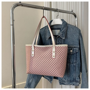 Detail of pink geometric pattern tote bag with white handles and gold rivet accents