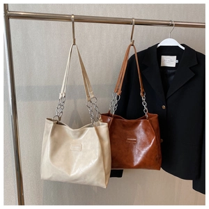 Détail de sacs fourre-tout minimalistes crème et marron avec chaînes argentées