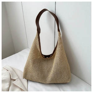 Détail d'un sac cabas en paille tissée avec des bandoulières contrastées en cuir marron