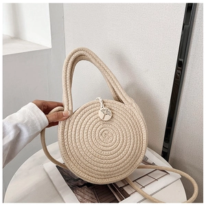 Détail d'un sac à main rond en paille beige avec motifs tressés et breloque en bois