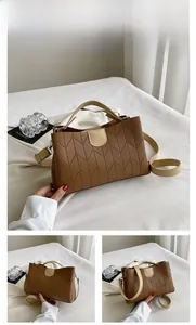 Detail view of brown tote bag with V-shaped stitching and creamy white top handle