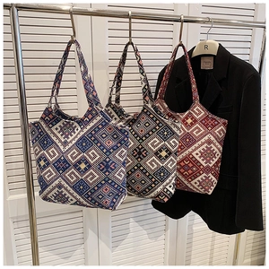 Detailed view of three canvas tote bags with ethnic geometric jacquard hanging on a rack