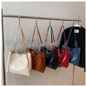 Cinq sacs cabas en crème, marron et marine sur un support en métal montrant le cuir brillant