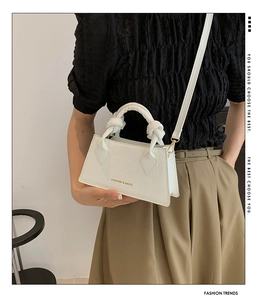 Détail du petit sac blanc gaufré crocodile avec poignée nouée et lettrage doré
