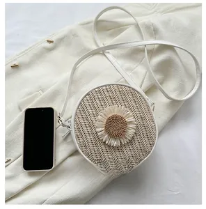 Détail du sac à bandoulière rond en paille avec lanière en cuir blanc et fleur