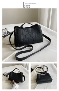Detail view of black tote bag featuring geometric V-shaped stitching and top handles