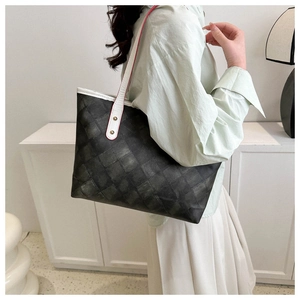 Détail du sac cabas gris avec lanières en cuir blanc et accents de bords rouges