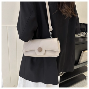 Detail view of cream rectangle baguette bag with silver hardware on a black blazer