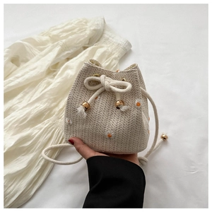 Close-up of woven bucket bag featuring delicate daisy embroidery and rope drawstring